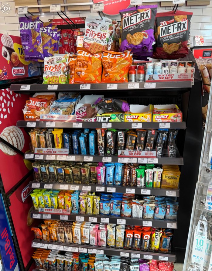 A crowded sports nutrition and protein bar rack at a Chevron gas station in San Jose.
